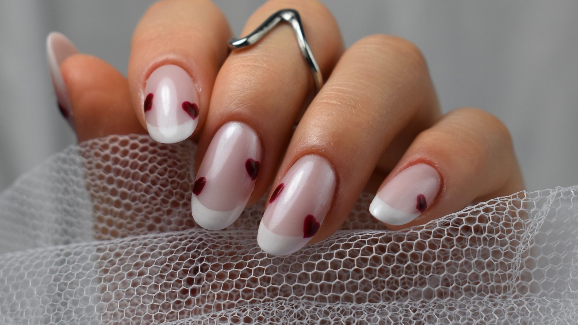 Melkwitte nagels met kleine rode hartjes, boven wit tule